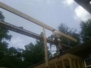 Carpenter setting a ridge beam over a new addition frame — Ice Dam Removal by Roofing Brothers in Islandia