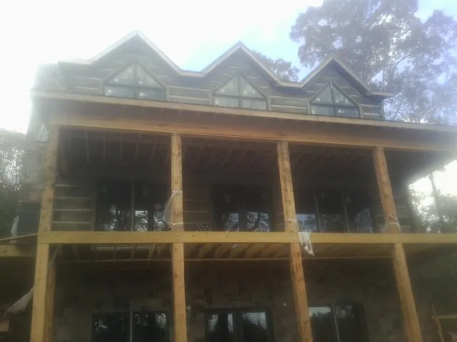 Dormers and porch framing on a large log home under construction — Roof Coating work by our crew in Islandia