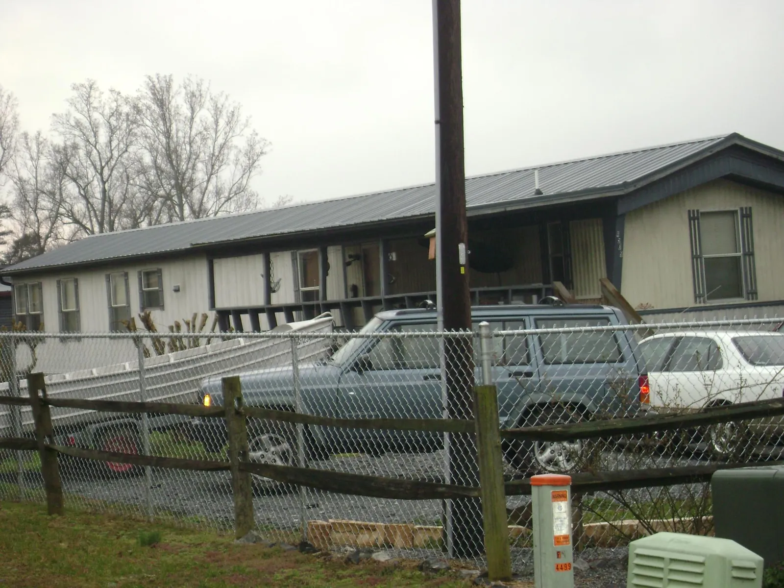 Dark metal roof on a long single story building behind a chain link fence in Islandia