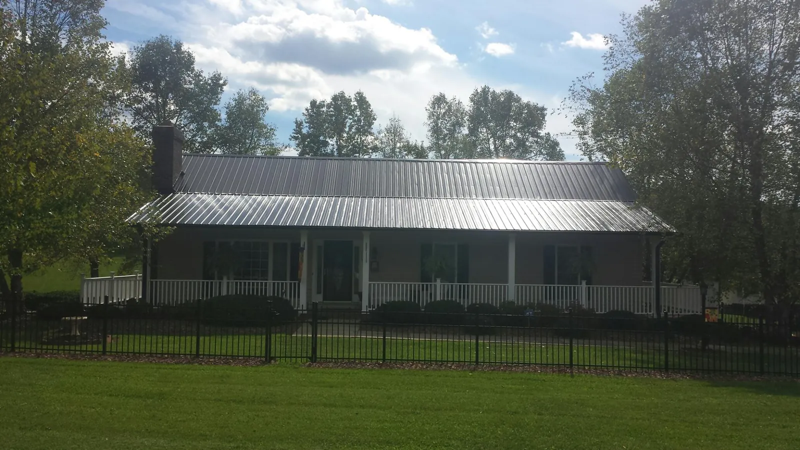 Gray metal roof on a brick ranch with a full width front porch — Gutter Guard Installation work by our crew in Islandia