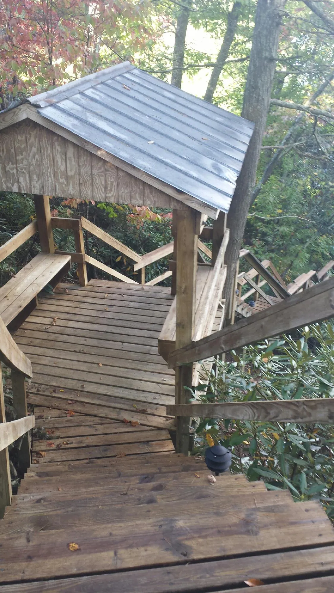 Metal roofed shelter over wooden steps on a wooded walkway — Skylight Repair & Installation work by our crew in Islandia