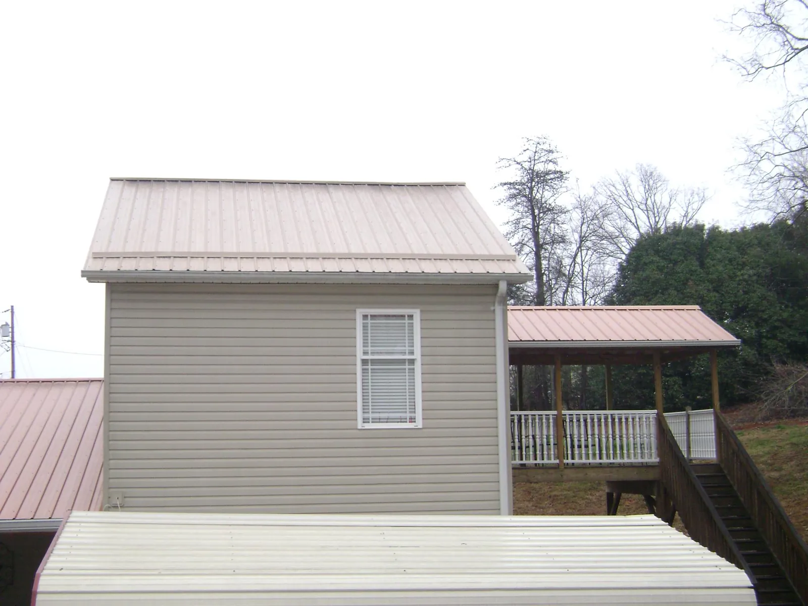 Tan metal roofs on a two story addition and attached porch, from a Roof Replacement job in Islandia