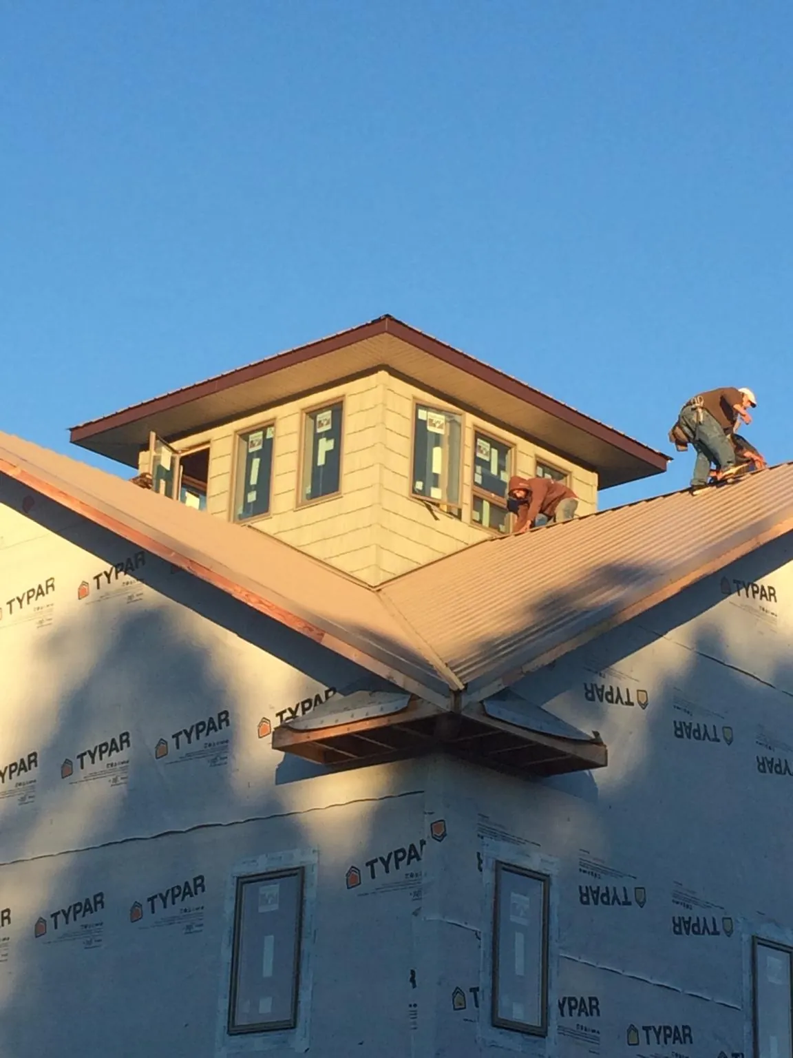 Roofers working around a rooftop cupola on a new metal roof at sunset — Roof Waterproofing in Islandia by Roofing Brothers